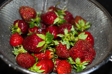 strawberries on a sieve under running water