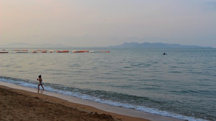 Fototapeta premium A small girl playing on the beach in the morning taking a blurred photo