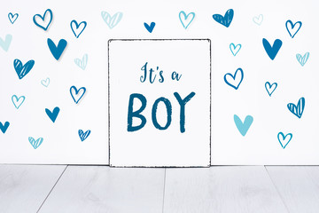 It's a boy new born baby text on sign board with cute little blue hearts on white background