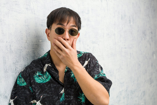 Young chinese man wearing summer outfit very scared and afraid hidden