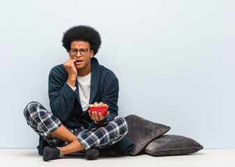 Young black man sitting and having a breakfast biting nails, nervous and very anxious