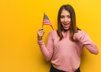 Young cute woman holding an united states flag surprised, feels successful and prosperous
