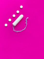 Tampon, feminine pain pills during menstruation on a pink background. Protection from unwanted pregnancy, ovulation