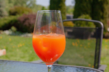 The cocktail glass on a garden table on a green grass lawn background. Spritz Veneziano champagne and orange juice cocktail