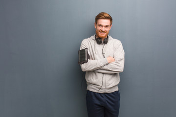 Young fitness redhead man crossing arms, smiling and relaxed