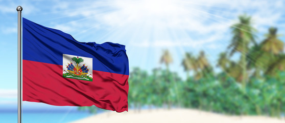 Waving Haiti flag in the sunny blue sky with summer beach background. Vacation theme, holiday concept.