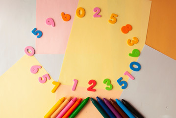 numbers and pencils on colorful background top view