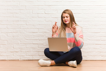 Young russian student woman sitting crossing fingers for having luck