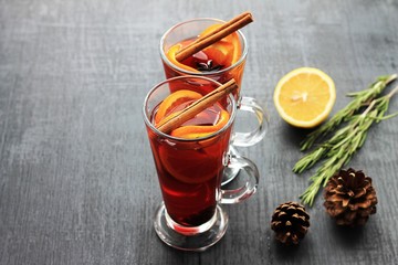 Sweet mulled wine for two person in glasses on a black background, decorated fir cones and rosemary.
