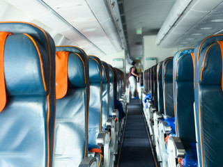  cabin airliner, the passage between the seats, blue leather seats. blurred background, passengers are preparing for flight