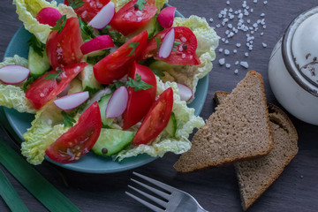 Summer salad of ripe vegetables and greens with black bread and spices on the table