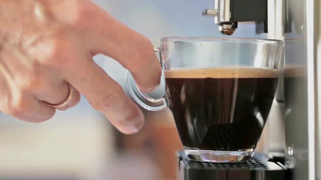 Preparation of natural delicious coffee in the automatic coffee machine. The man takes a cooked Cup of hot espresso. A charge of vivacity every day. Good morning