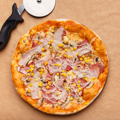 Delicious Pizza And Cutter On Craft Paper Background