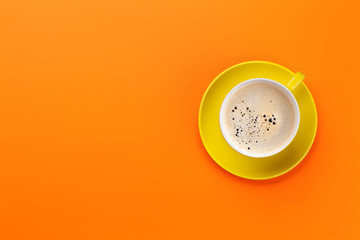 Yellow coffee cup over orange background