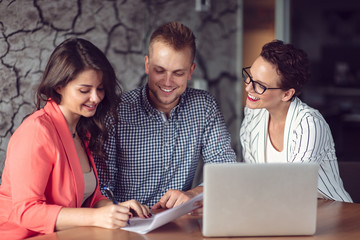 Investment adviser giving a presentation to a friendly smiling young couple seated at her desk in the office