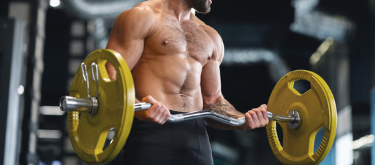 Fototapeta na wymiar Muscular bodybuilder exercising with heavy barbell in gym