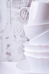 Heap of white ceramic crockery set against the white wooden background