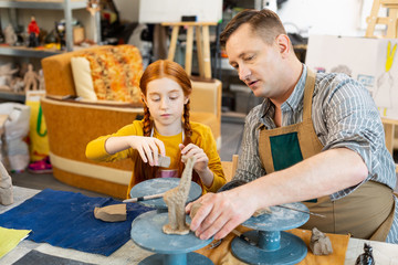 Daughter and father modeling clay animals in workshop