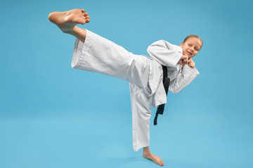 Obraz na płótnie Canvas Girl in white kimono performing kick foot forward.