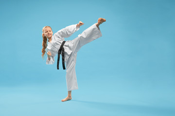 Karate girl in white kimono practicing martial arts. © serhiibobyk