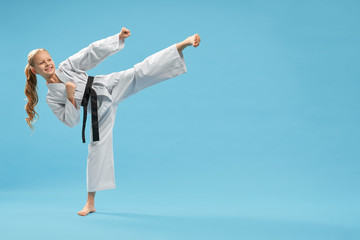 Positiive karate girl practicing kick foot forward. 