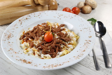 Pasta (gnocchi) with julian meat and spicy tomato sauce and basil