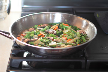 Stir fry vegetables cooking in a stainless steel pan.