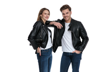 Positive couple laughing while holding their hands in their pockets