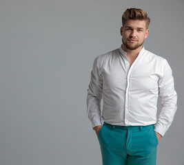 Charming man standing and holding both hands in his pockets