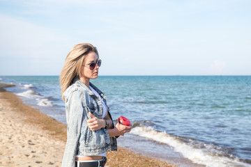 young attractive blonde female with cup of coffee looks at the sea