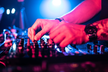 Close up of DJ Hands Controlling Music Table in a Night Club.