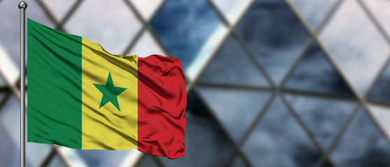Senegal flag waving in the wind against blurred modern building. Business concept. National cooperation theme.