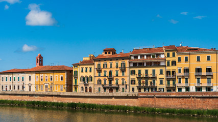 Fototapeta na wymiar Colorful old houses along the bank of the Arno river. Cityscape in Pisa, Italy on a sunny summer day.