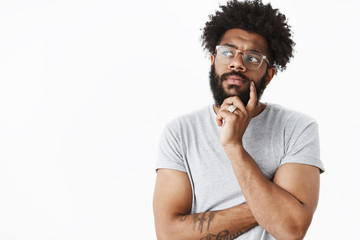 African american guy in glasses making plan in mind thinking up grocery list holding hand on beard...