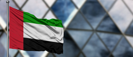 United Arab Emirates flag waving in the wind against blurred modern building. Business concept. National cooperation theme. © sezerozger
