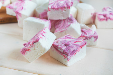 tender airy white pink purple large squares of marshmallows on a white background, sweet trendy food dessert