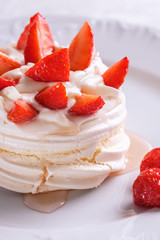 Pavlova dessert with strawberries on a white plate.