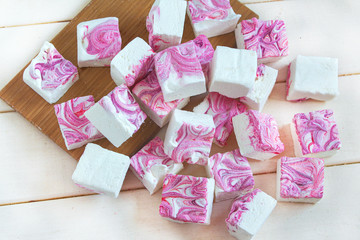 tender airy white pink purple large squares of marshmallows on a white background, sweet trendy food dessert