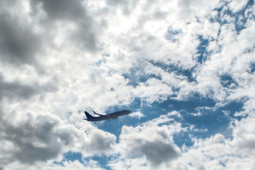 on the blue sky with white fluffy clouds the plane flies
