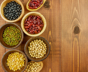 Flat lay,top view assorted beans including red bean,soybeans,black beans,mung beans on brown,beige wooden background with copy space 