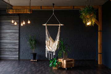 Brutal modern interior in a dark color with hammock. Loft style living room