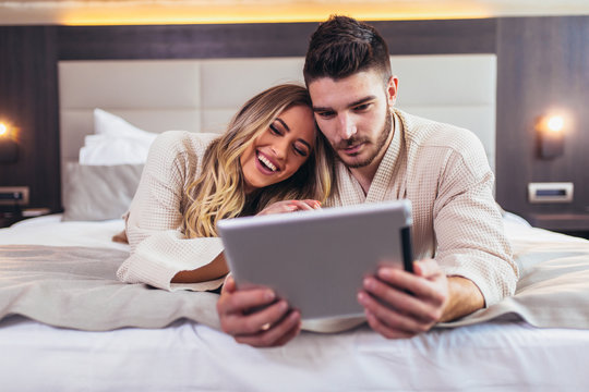 Couple In Hotel Room Reading Room Service Menu Together In Bed