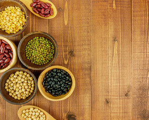 Flat lay,top view assorted beans including red bean,soybeans,black beans,mung beans on brown,beige wooden background with copy space 