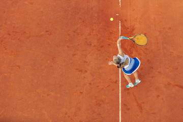 Aerial shot of a female tennis player on a court during match. Young woman playing tennis.High angle view.