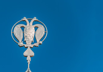 Fototapeta na wymiar Coat of arms of Russia, silver double-headed eagle against the background of blue sky. Silver Russian heraldic symbol, background with copy space.