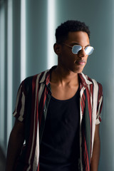 young handsome attractive guy in sunglasses posing in the neon light of the night city