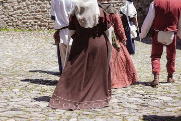Group of unrecognizable people dressed in medieval costumes walking down an ancient street