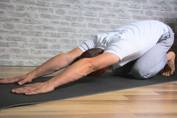Man exercising stretching back yoga pose on the  mat.