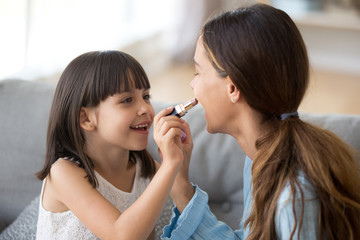 Funny young mom and preschooler daughter do makeup together