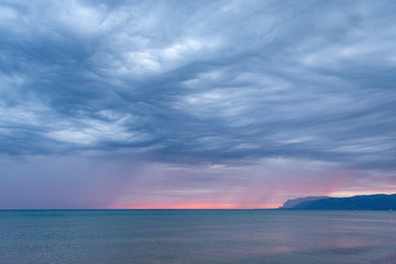 Obraz premium Scenic gray-blue clouds during sunrise over coastline with sandy beach and clear sea water in Alcamo Marina, small town in Sicily, Italy, summer vacation destination